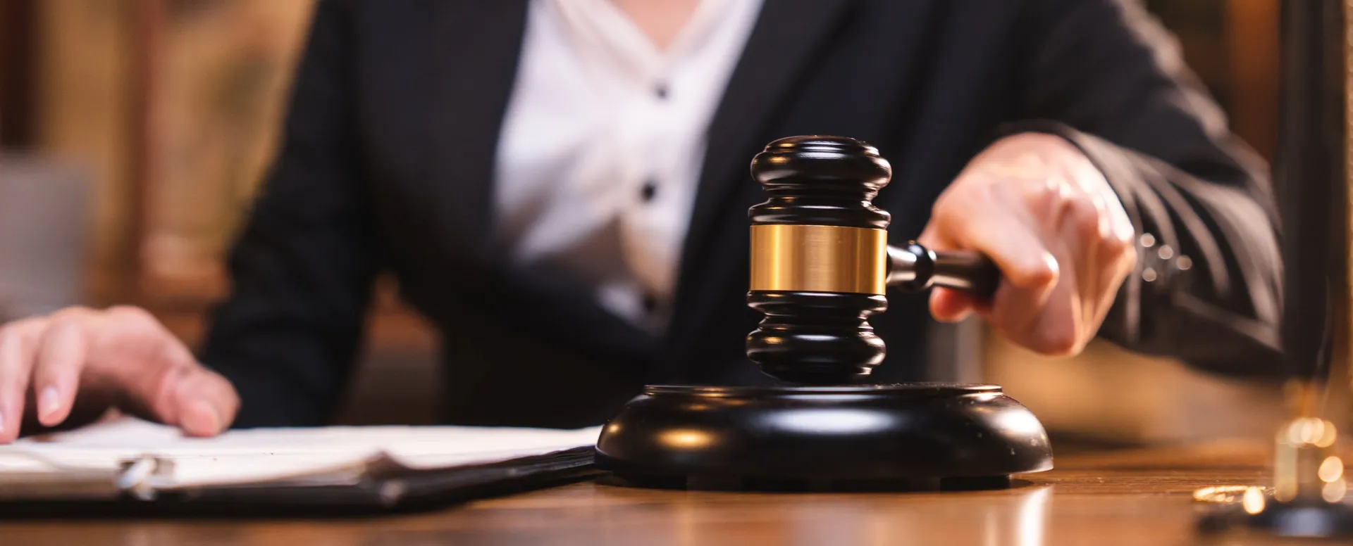 A judge’s hand bringing down a gavel beside court papers