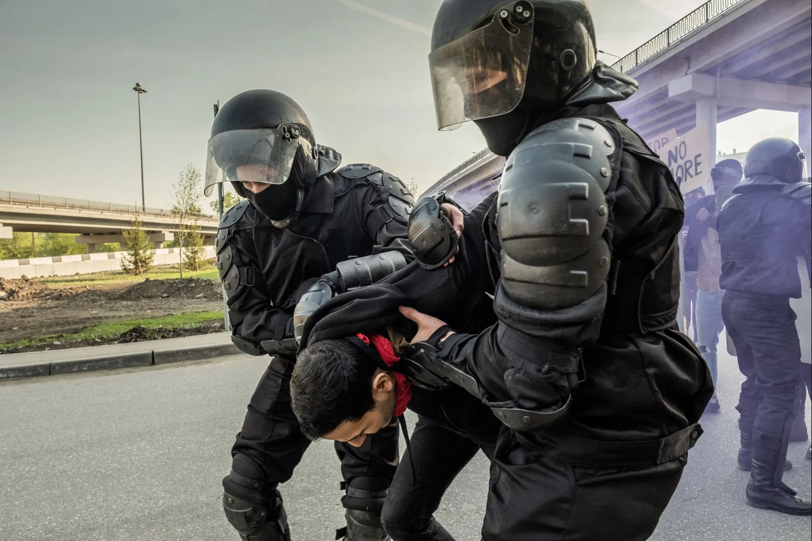 Two officers restraining a man while others stand by